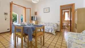 A room with a dining table set for two, a bed with a floral bedspread, and a bathroom visible through an open door. - 3447 Villetta Grazia by Barbarhouse (Nardò)