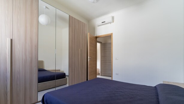 A bedroom with a large bed, a wardrobe, and a mirror. - 3463 Villetta Naomi by Barbarhouse (Porto Cesareo)
