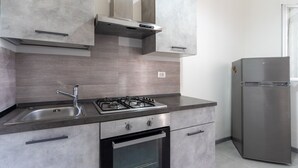A modern kitchen with a stainless steel gas stove, a built-in oven, and a refrigerator. - 3463 Villetta Naomi by Barbarhouse (Porto Cesareo)