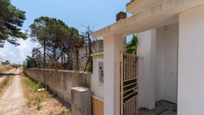 A building with a gated entrance, a concrete wall, and a gravel path. - 3463 Villetta Naomi by Barbarhouse (Porto Cesareo)