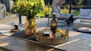 A wooden table with a vase of flowers, a bottle, and a basket of eggs and bread. - The Longsands Home • Coastal w/ Hot Tub (Tynemouth)