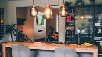 A modern kitchen with a wooden island, pendant lights, and a view of a living room.