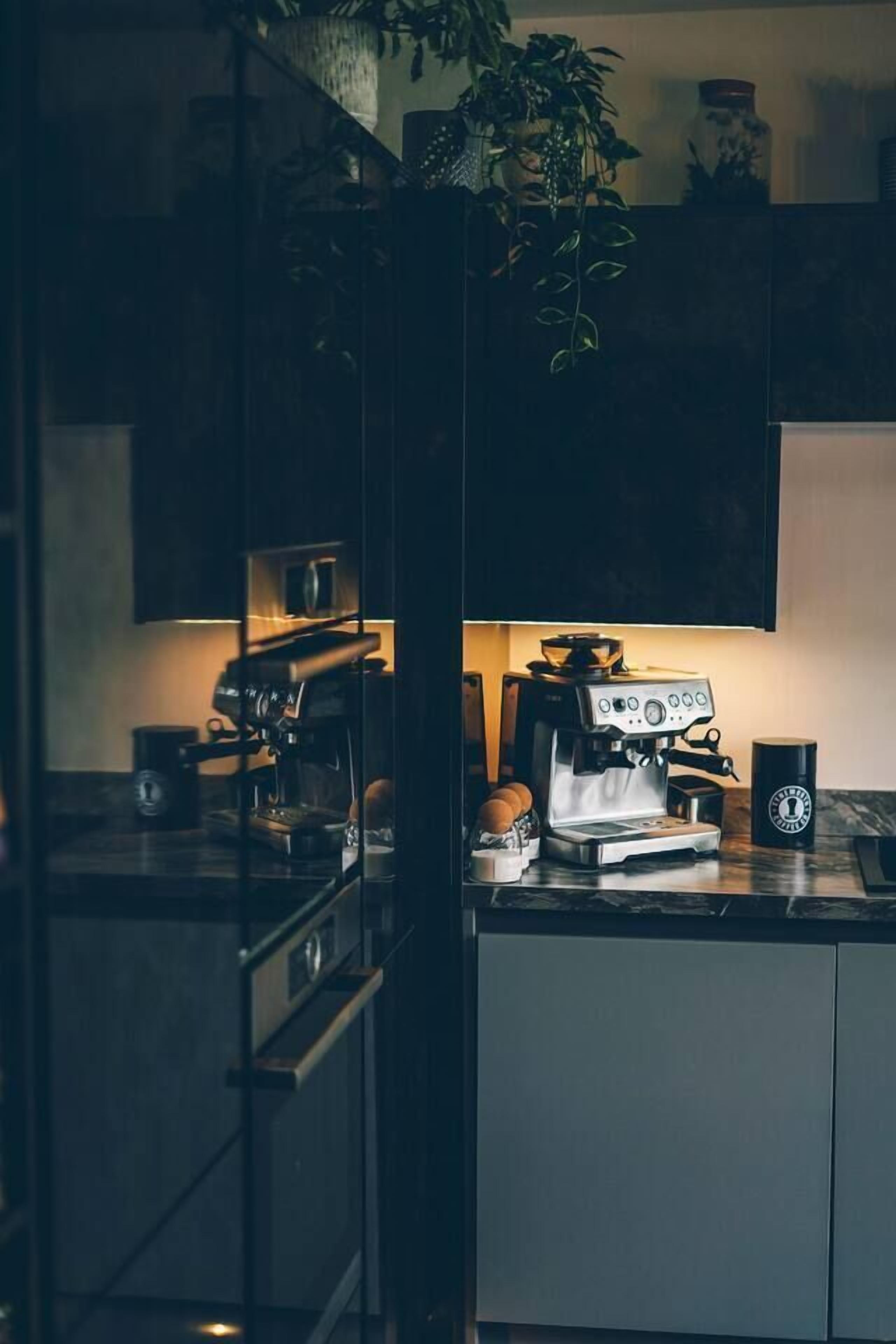 A modern kitchen with a coffee machine, a cup, and a plant.