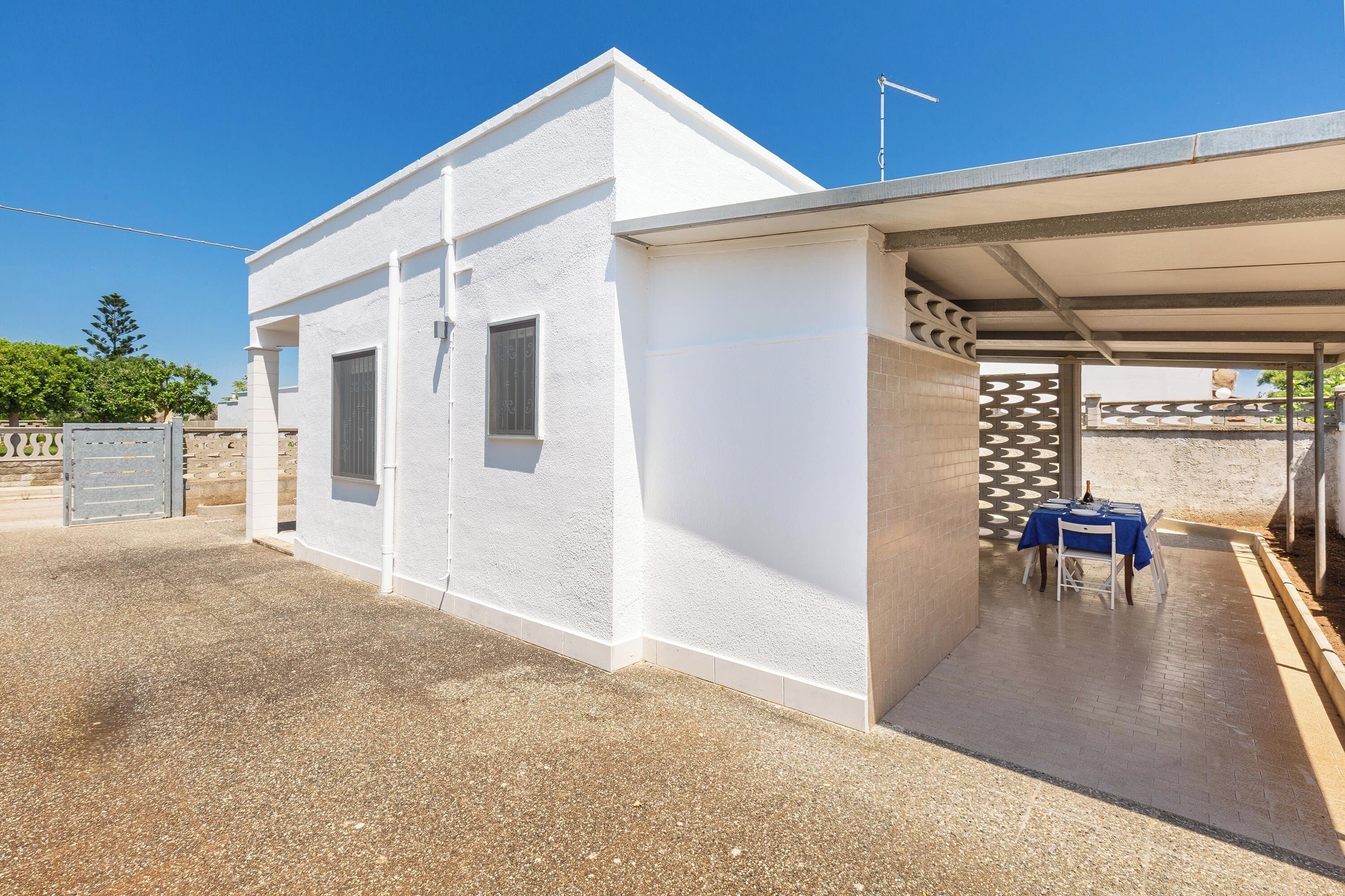 A white building with a covered outdoor seating area and a gated entrance.
