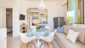A modern kitchen with a round dining table, white chairs, and a hanging light fixture. - 3592 Villetta Ninì by Barbarhouse (Porto Cesareo)