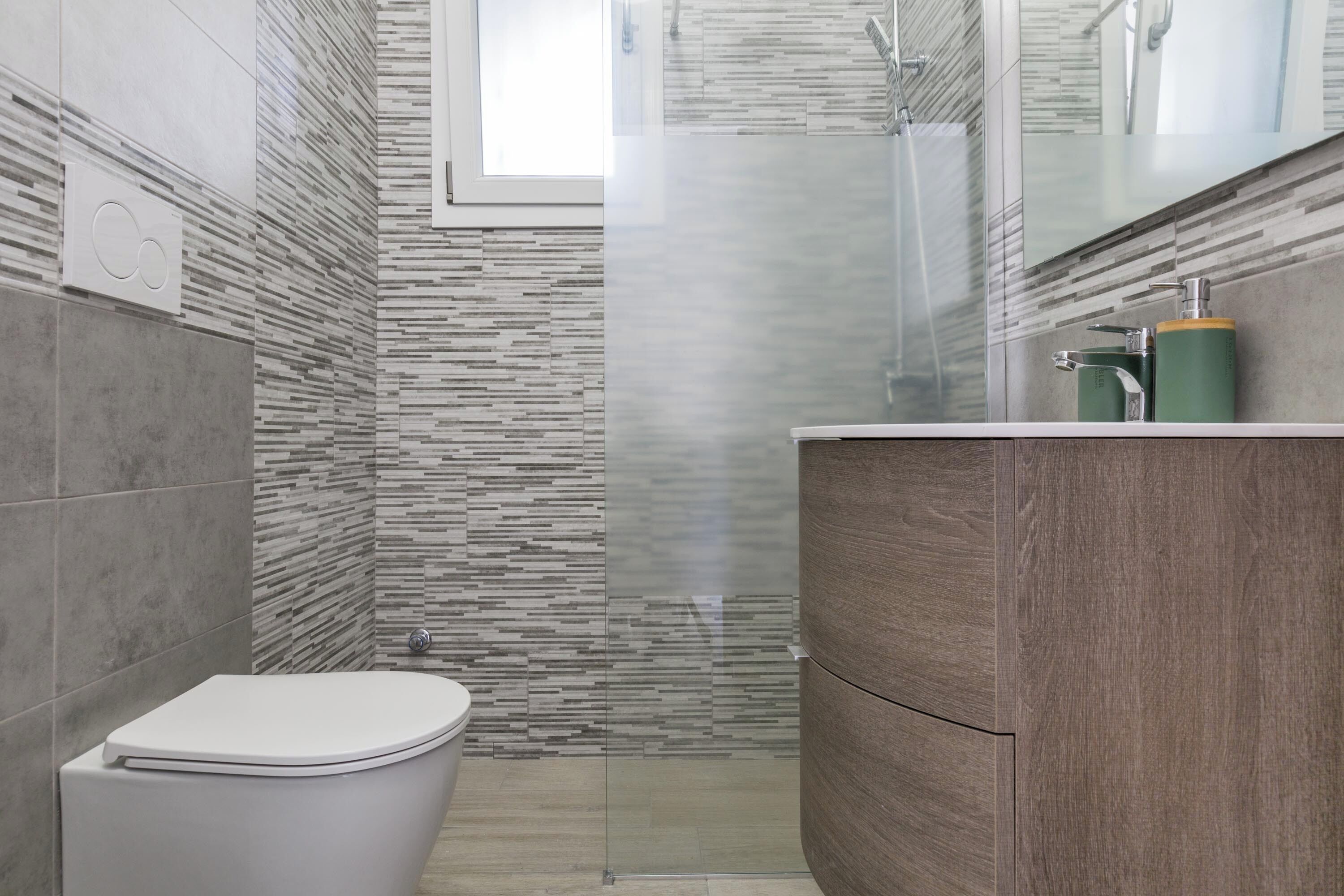 Ein modernes Badezimmer mit Toilette, Dusche und Waschtisch mit Spiegel.