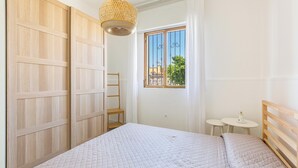A bedroom with a bed, a window with a view, a small table, and a chair. - 3592 Villetta Ninì by Barbarhouse (Porto Cesareo)