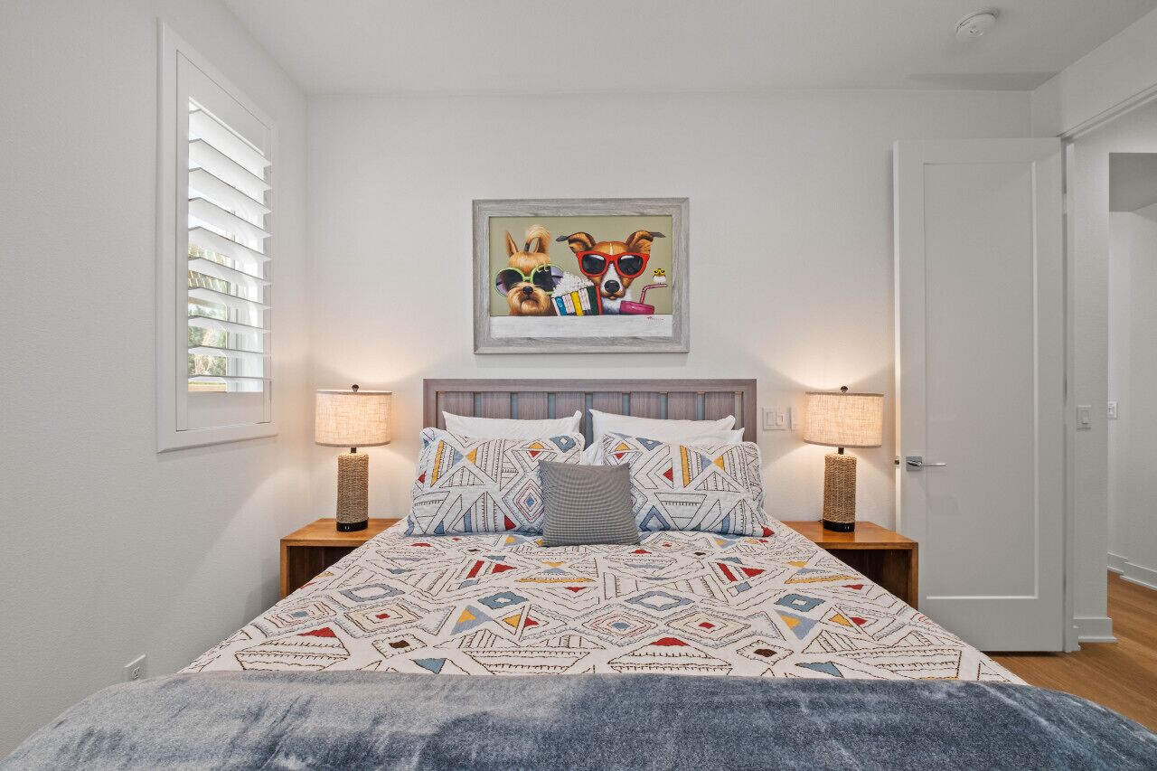Drift off in the bright bedroom w/ patterned bedding & soft bedside lighting.