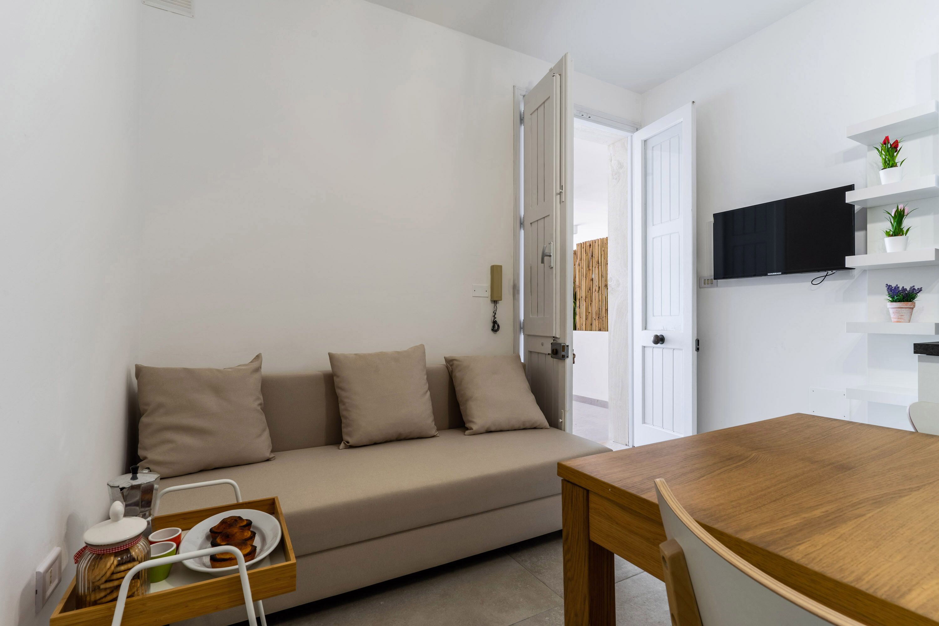 Un salon moderne avec un canapé, une table à manger en bois et un téléviseur fixé au mur.
