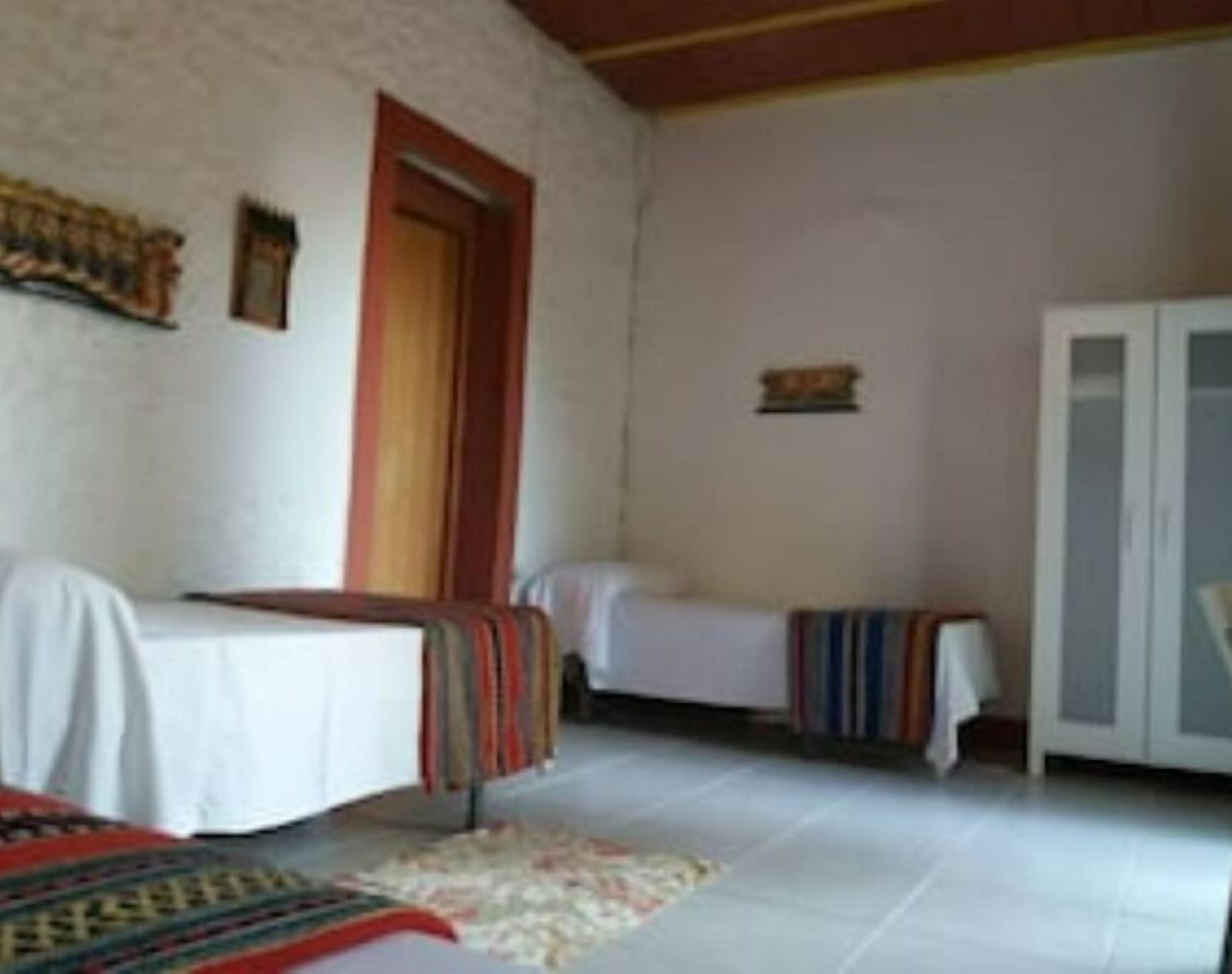 Een kamer met twee bedden, een kledingkast en een klein vloerkleed.