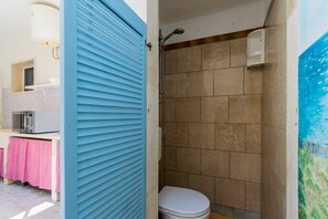Une salle de bain avec une douche, des toilettes et un lavabo, ainsi qu’une serviette rose.