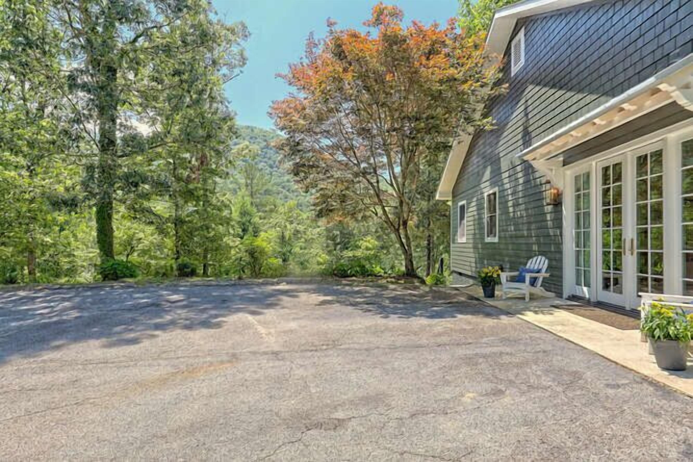 A house with a covered driveway, surrounded by trees and a well-maintained lawn.