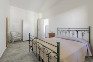 Een slaapkamer met een bed, een stoel, een kledingkast en een nachtkastje.