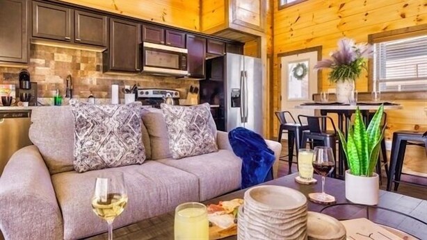 A cozy cabin interior with a living area, kitchen, and dining space. - Fall Dollywood Magic! HotTub, Arcade, Game Room, Dog OK, 2 Suites, A+ location (Sevierville)