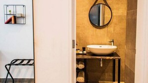 Ein modernes Badezimmer mit einem großen Spiegel, einem runden Waschbecken und einem Handtuchhalter.