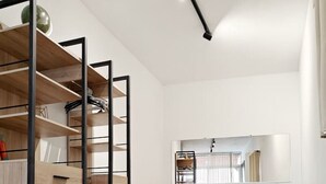 A modern bedroom with a bed, a green sofa, a wooden wardrobe, and a mirror.
