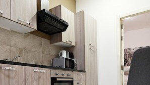 Una cocina moderna con armarios de madera clara, horno empotrado y microondas.