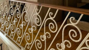 A wooden staircase with ornate white railings and a stone wall in the background. - Serenity 2  studio apartment with small terrace (Ħal Qormi)