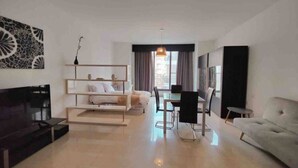 A modern living room with a sofa, a dining table with chairs, a TV, and a large artwork on the wall. - Seaview apartment Sliema (Tas-Sliema)