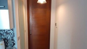 A hallway with a wooden door, a tiled backsplash, and a pendant light. - Seaview apartment Sliema (Tas-Sliema)