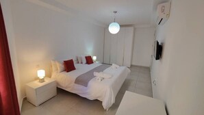 Ein modernes Hotelzimmer mit Bett, Nachttisch und Flachbildfernseher.