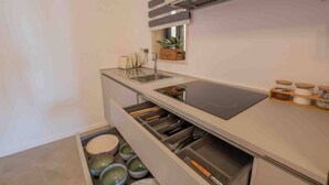 Een kleine keuken met een inbouwfornuis, een spoelbak en opbergladen.