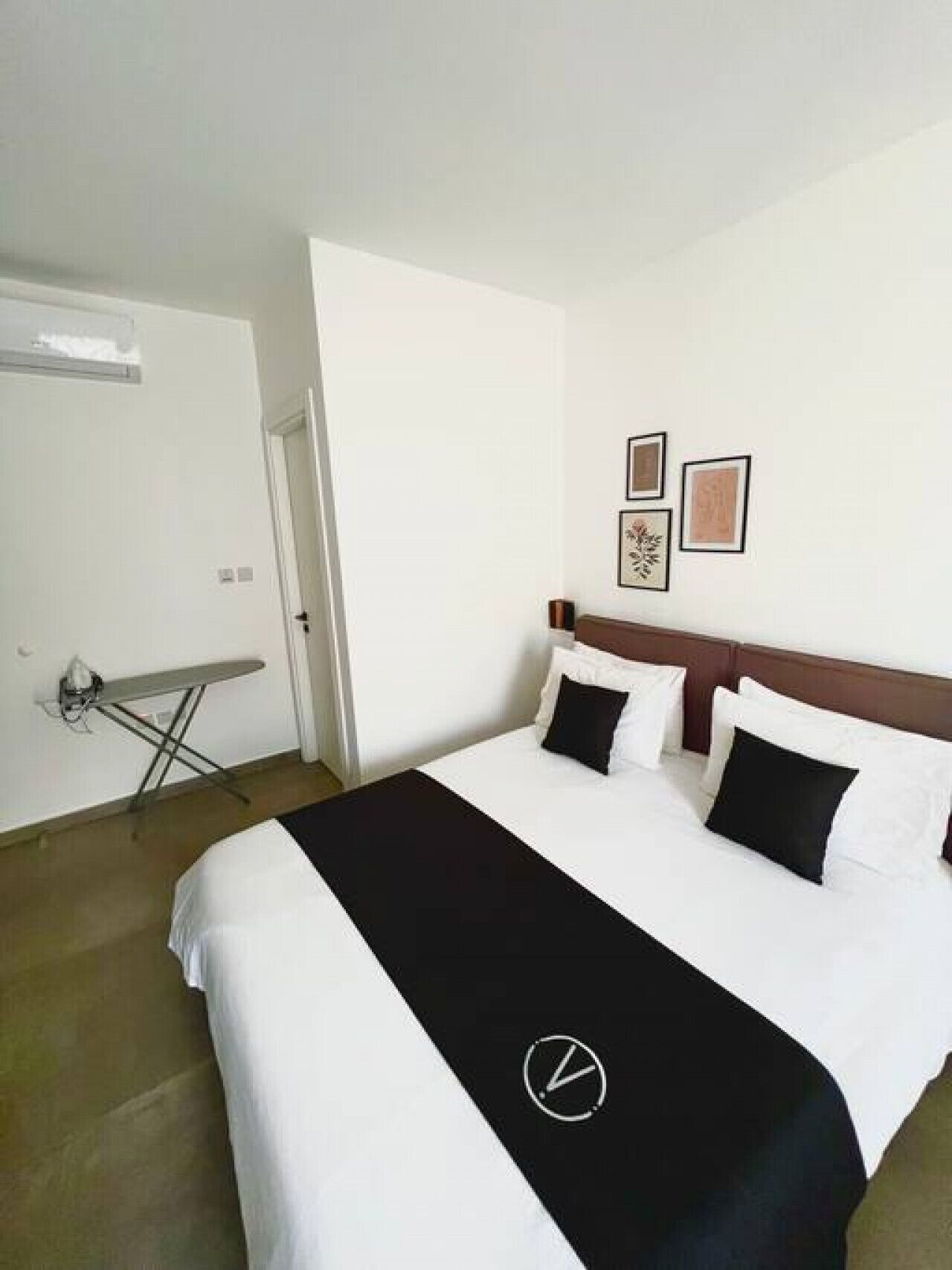 Une chambre d’hôtel avec un lit, un téléviseur à écran plat, une petite table et une porte.