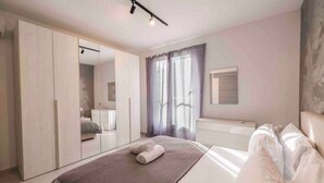 Een moderne slaapkamer met een groot bed, een garderobe, een kaptafel en een raam met gordijnen.