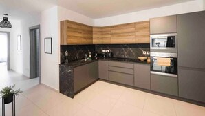 Een moderne keuken met donkere marmeren aanrechtbladen, houten kastjes en roestvrijstalen apparatuur.