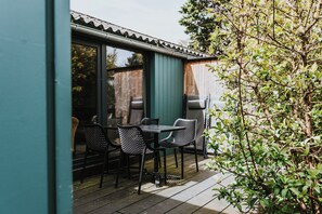 Een terras met een tafel, stoelen, een barbecue en een groene wand.
