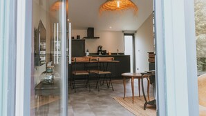 A modern kitchen with a bar area, a dining table, and a hanging light fixture. - Bel Air, Accès Piscine - Jacuzzi Privé - Terrasse (Criel-sur-Mer)