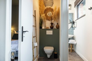 A narrow hallway leading to a bathroom with a toilet, a sink, and a mirror. There is a ladder leaning against the wall and a small stool with towels. - Appartement - Piscine - Terrasse, Beau Séjour (Criel-sur-Mer)