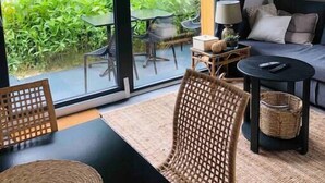 A modern living room with a sofa, a coffee table, and a dining table. There is a large sliding glass door leading to an outdoor patio with a table and chairs. - Appartement - Piscine - Terrasse, Beau Séjour (Criel-sur-Mer)