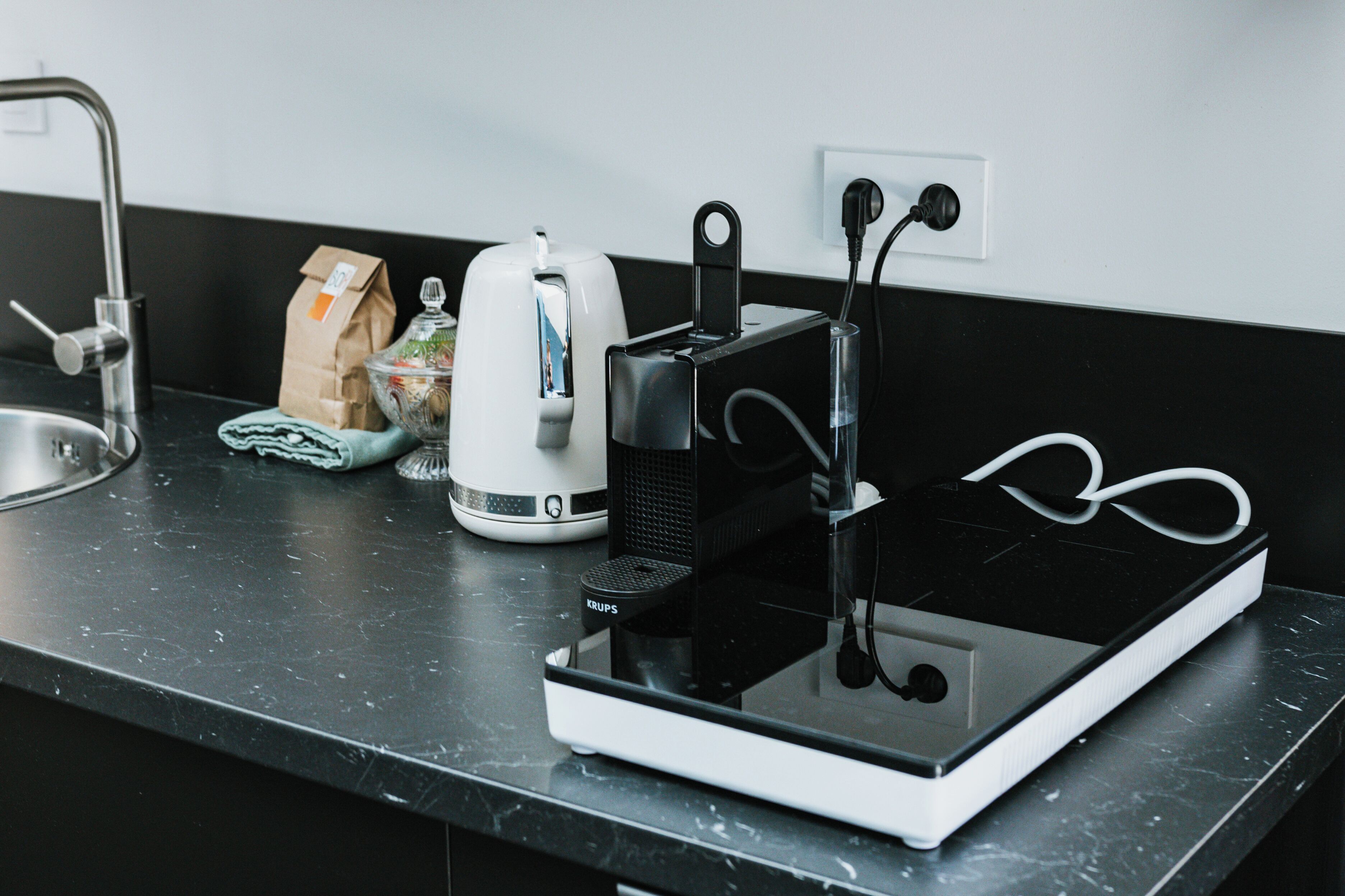 A kitchen counter with a coffee maker, a kettle, a toaster, and a power strip.