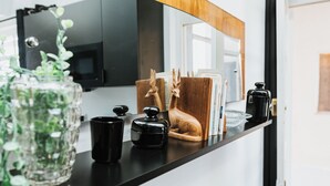 Un comptoir de cuisine avec un vase en verre, une tasse noire, une figurine de cerf en bois et une machine à café.