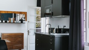 Une cuisine moderne avec des meubles de couleur noire, un four à micro-ondes et un évier. On y trouve également une commode en bois et une chaise dans un coin.