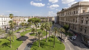 Un edificio grande e histórico con arquitectura clásica, rodeado de palmeras y un patio bien cuidado.
