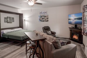Une pièce confortable avec un lit, un canapé, une table, une chaise, un téléviseur et une cheminée.
