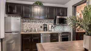 Una cocina moderna con armarios oscuros, electrodomésticos de acero inoxidable y un salpicadero de mosaicos.