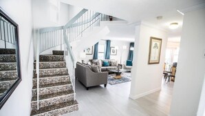 Amplia sala de estar con escalera, un sofá gris y una mesa de centro.
