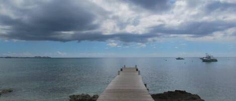 A concrete pier extending into calm waters with a clear sky above.
