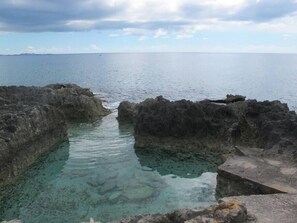 A coastal view with clear water between rocky formations. - Fabulous one Bedroom in West Bay (West Bay)