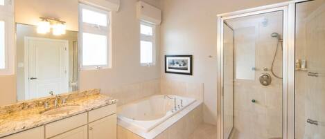 A bathroom with a large bathtub, a shower enclosure, and a vanity with a sink and mirror.