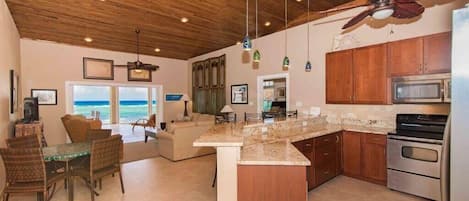 A spacious kitchen with wooden cabinets, a granite countertop, and a ceiling fan.