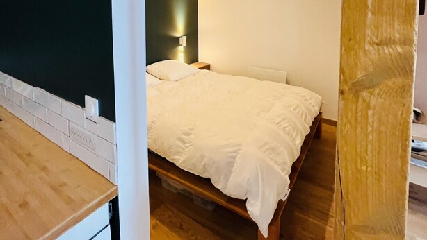 Ein Schlafzimmer mit einem hölzernen Bett, einem Nachttisch und einer Wandleuchte.