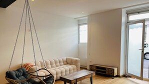 Ein modernes Wohnzimmer mit Hängesessel, Sofa und Couchtisch aus Holz.