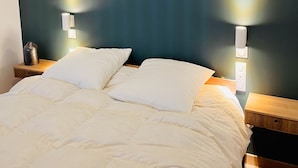 Ein Bett mit weißer Bettwäsche, zwei Nachttische und Wandleuchten.