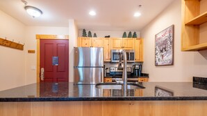Una cocina moderna con electrodomésticos de acero inoxidable, armarios de madera y encimera de granito.