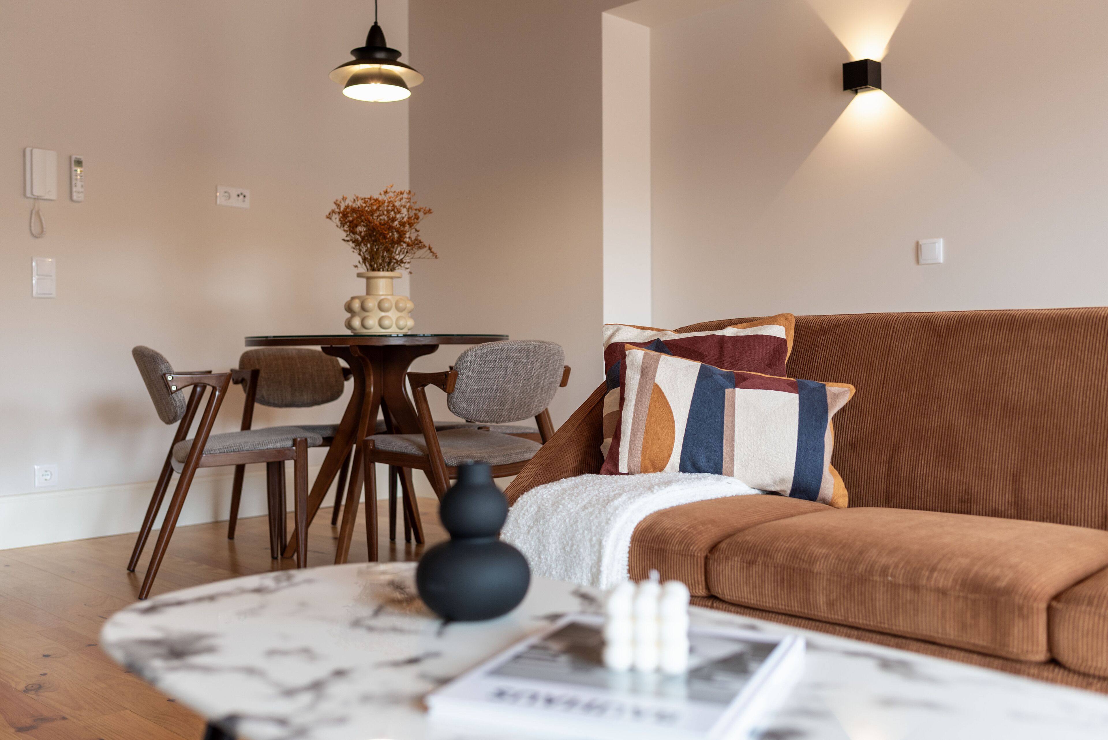 Un salon moderne avec un canapé marron, une table basse ronde et un coin repas comprenant une table et des chaises.