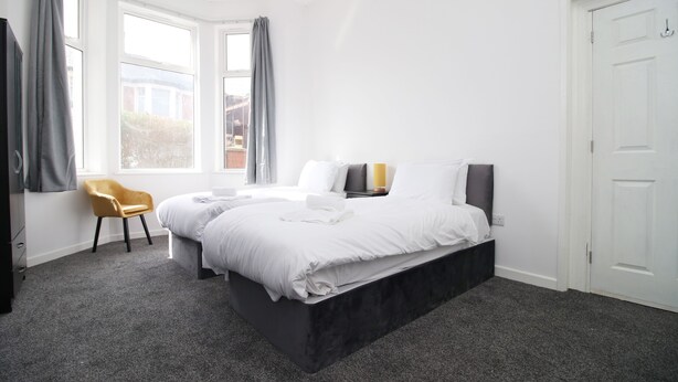 A bedroom with a large bed, a chair, and a window. - Rugby Road by Tŷ SA (Newport)